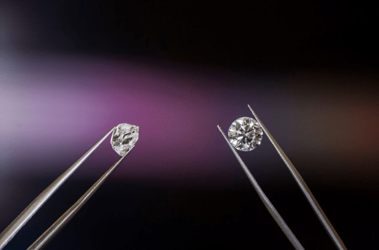 Close-up of two diamonds held by tweezers against a dark purple gradient background while jewelry work is performed.